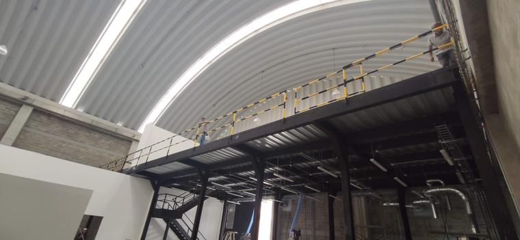 Interior de bodega con mezanine metálico y cubierta curva en teja