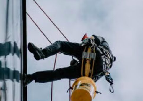 Operario en rappel apoyado sobre la fachada acristalada de un edificio