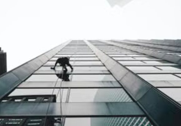 Torre de oficinas en contrapicado con un operario descolgado sobre el vidrio